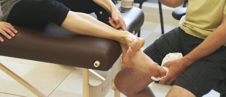 A PT checks out a dancer's sprained ankle on a table