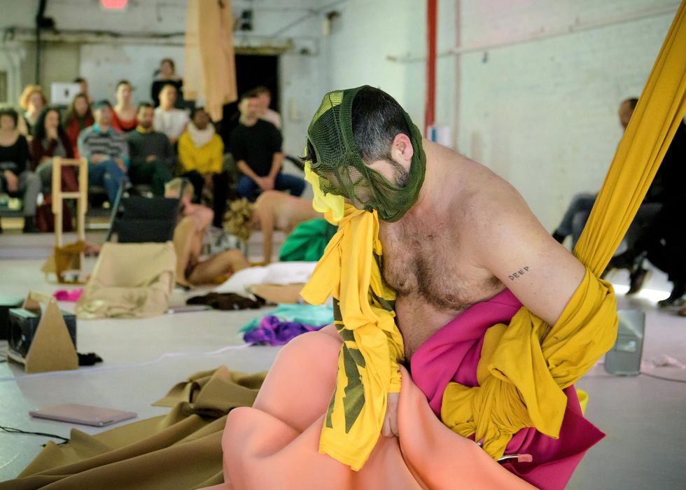 Barechested, Miguel Gutierrez gathers different fabrics to himself, one mesh fabric covering his face