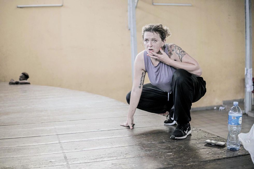 Abby Zbikowski crouches to the floor, one hand down for balance, the other grazing her mouth as she looks intently beyond the camera