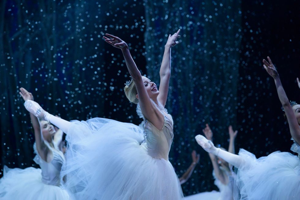 Blonde dancer Dawn Atkins in a high arabesque and bright smile dances Nutcracker's snow scene.