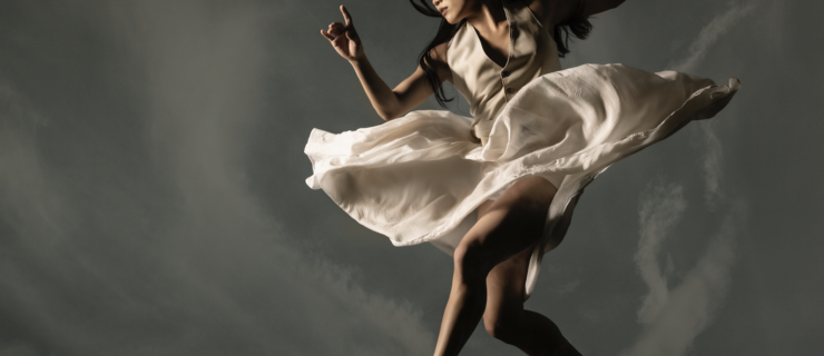 Cora Cliburn jumps up in the air, her flowy white dress swirling around her hips