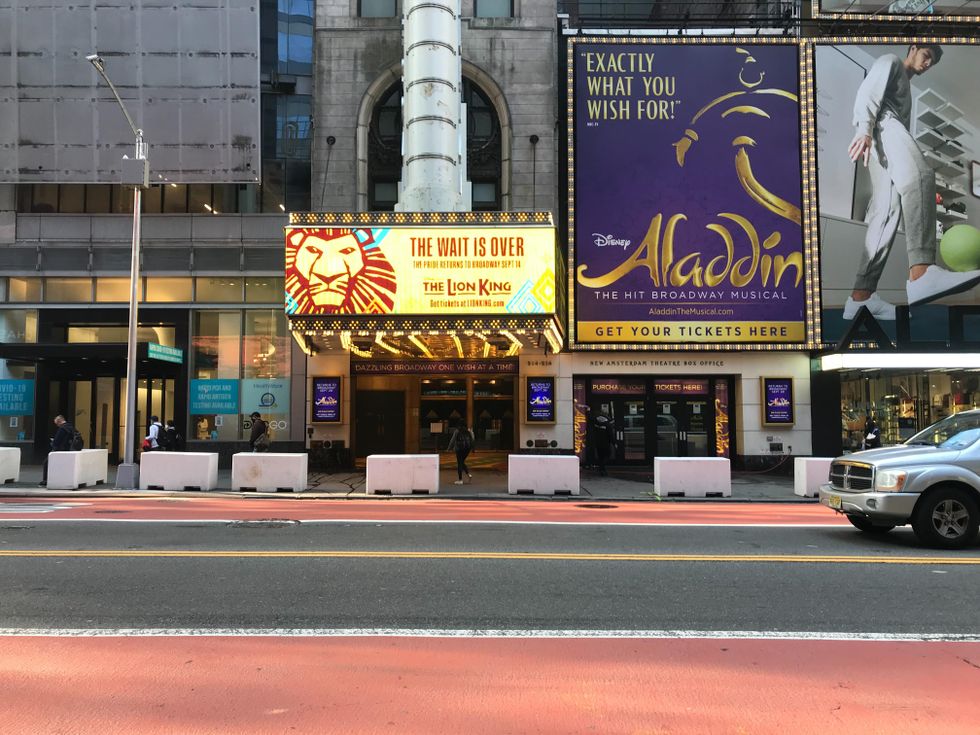 The Lion King's Broadway marquee says "The Wait Is Over" with a picture of a lion, next to an ad for Aladdin above a mostly empty New York street