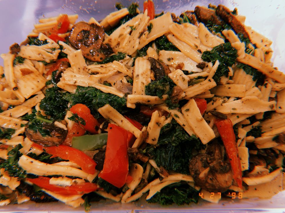 Yellow pasta mixed with red peppers, green spinach and mushrooms