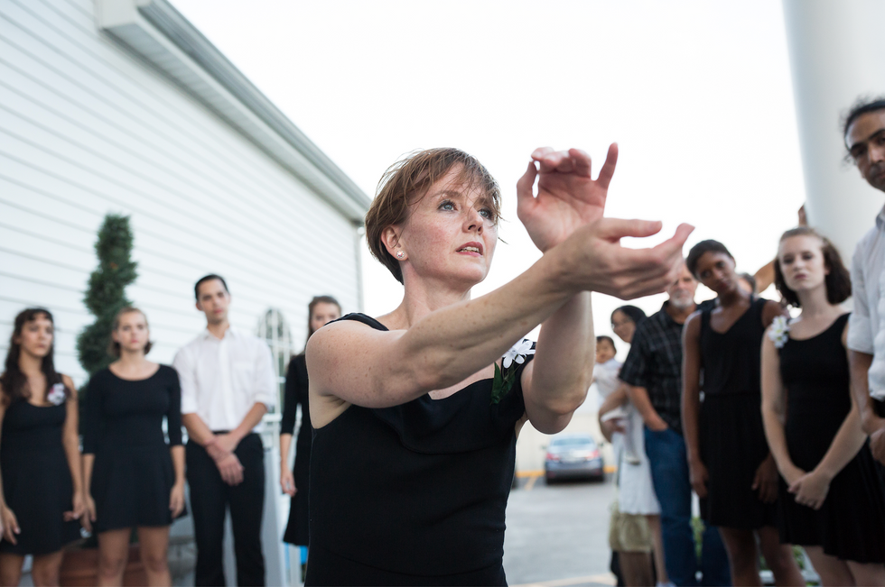 Jennifer Mabus reaches her hands out in front of her face, a crowd of people wearing white and black surround her