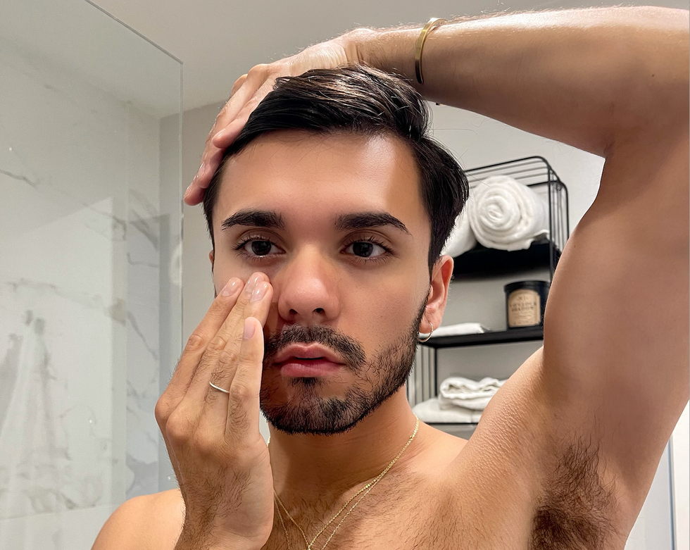 Omar Rivera rubs his face skin below his eye in a bathroom