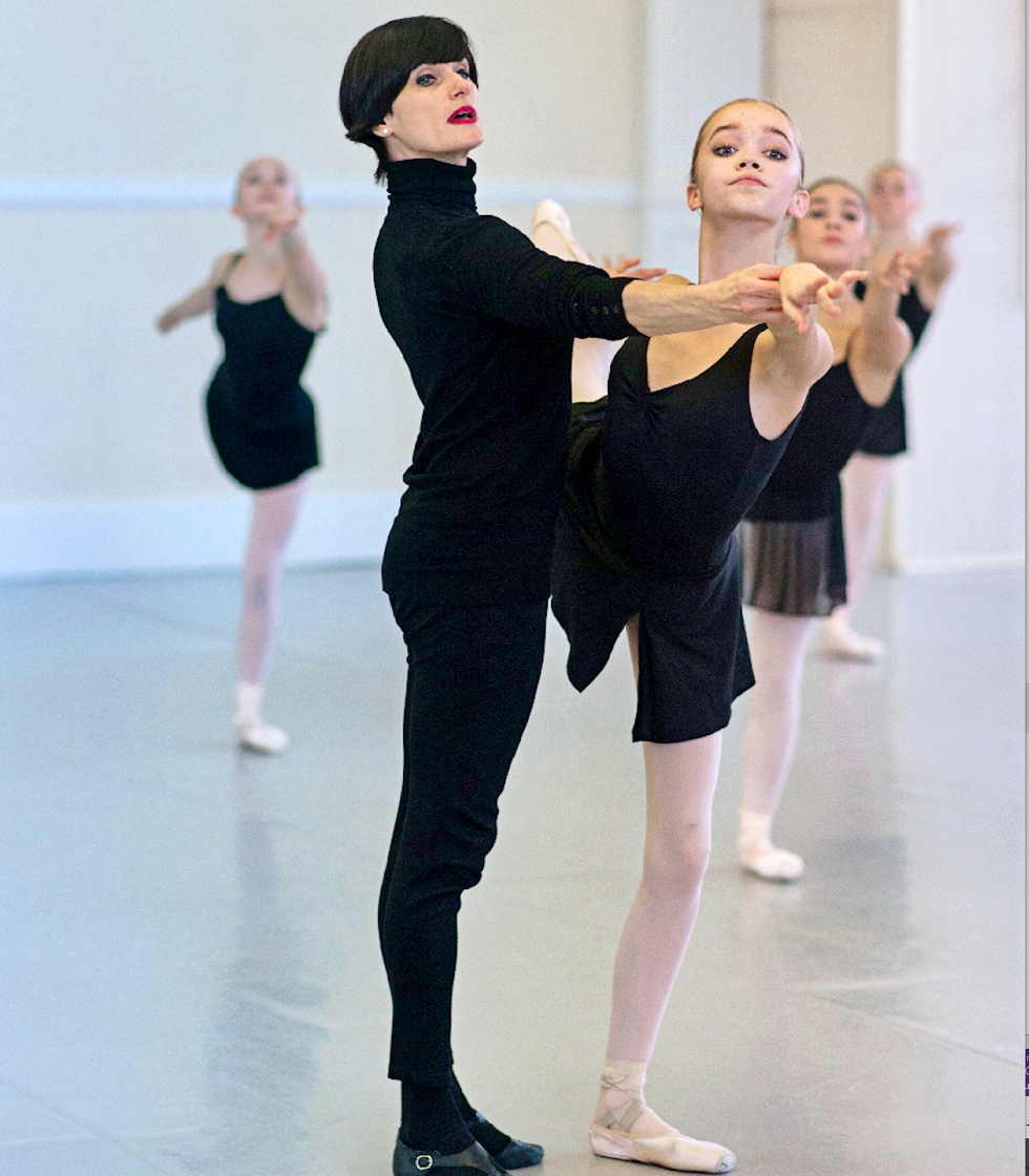 Alexandra Koltun, in all black, corrects a young ballet dancer's port de bras in arabesque