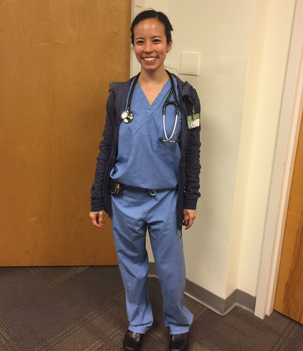 Madelyn Ho stands in blue scrubs with a stethoscope around her neck