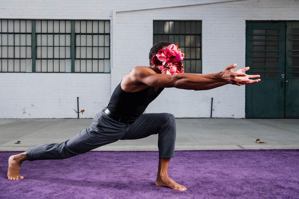 Anthony Lee Bryant dances on a purple carpet, a mask of roses on his face