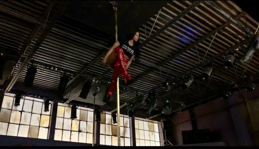 Evans clings onto a gold pole between her thighs high up in a warehouse