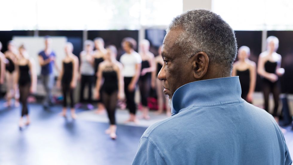 A closeup of Donald Byrd from behind, a row of dancers in the background