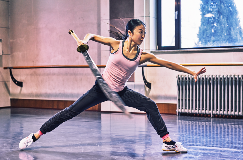 Chien-Pott in rehearsal holding a fake sword, lunging forward as if about to use it.