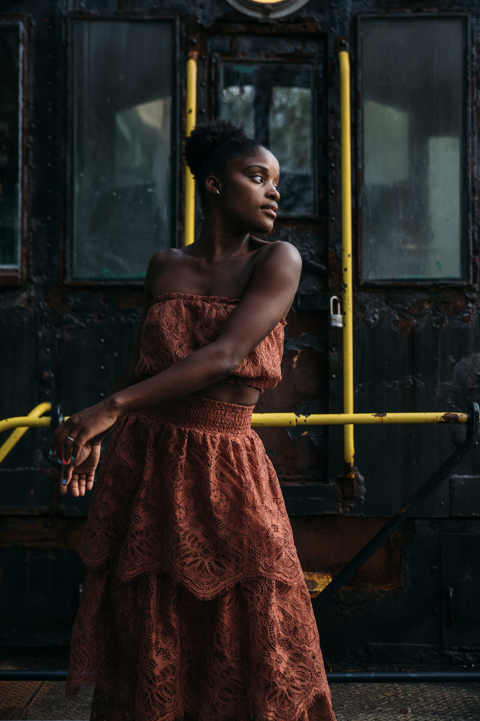 Ingrid Silva stands in front of an old train car, leaning to her left with her hands flowing in the opposite direction.