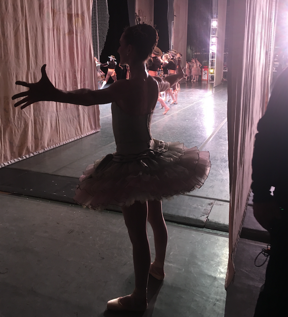 Tricia Albertson stretches her arms to the sides backstage in the wings