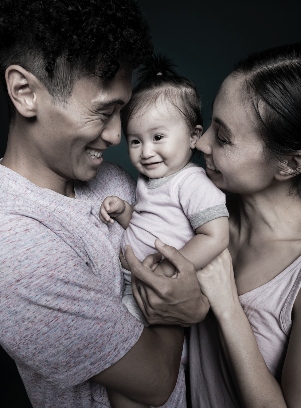 Close-up of Keone and Mari holding their daughter and smiling