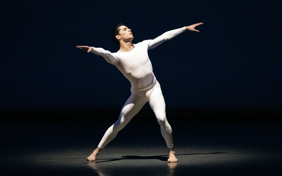 Jovani Furlan in a white unitard, lunging  in a stream of light