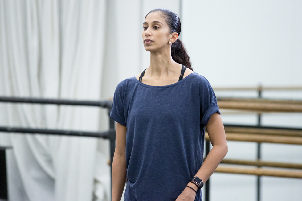 Alicia Graf Mack stands at attention in a studio, with ballet barres behind her