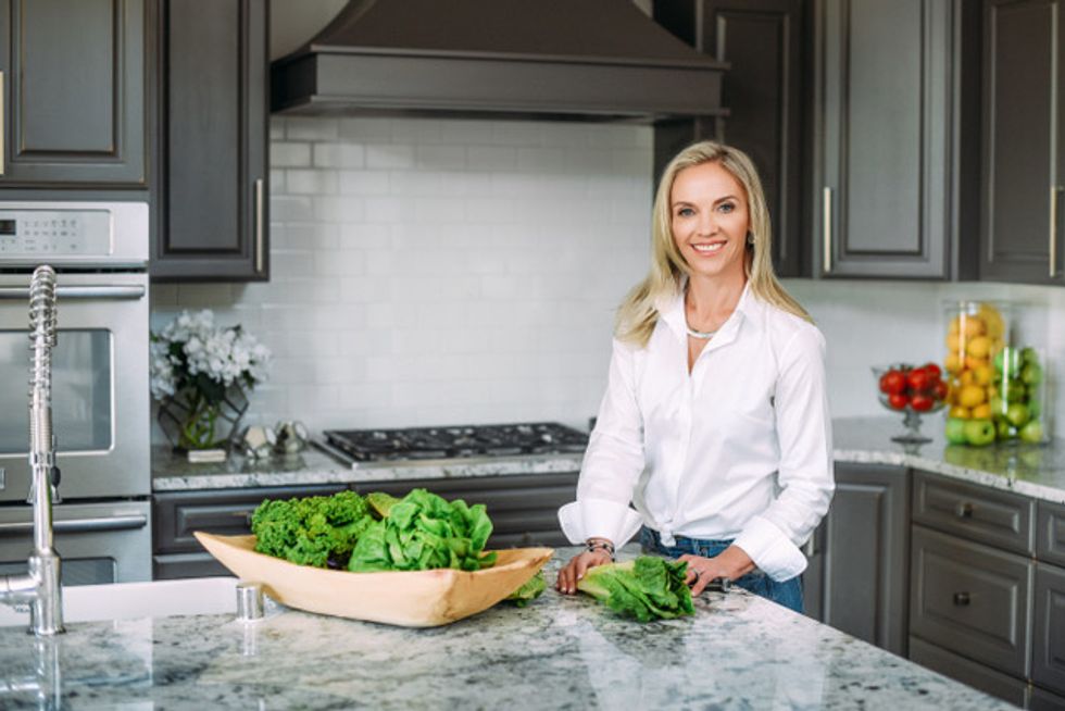 Kristin Koskinen in the kitchen with several heads of lettuce on the counter in front of her.