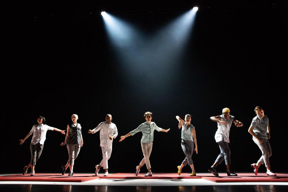 a lineup of tap dancers across the stage, in lights