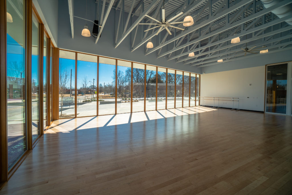 A sunlit dance studio with floor-to-ceiling windows