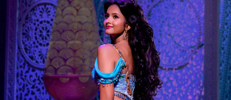 Shoba Narayan in costume as Jasmine. She is wearing a turquoise bare-shouldered top and pants, a tiara and has long dark hair.