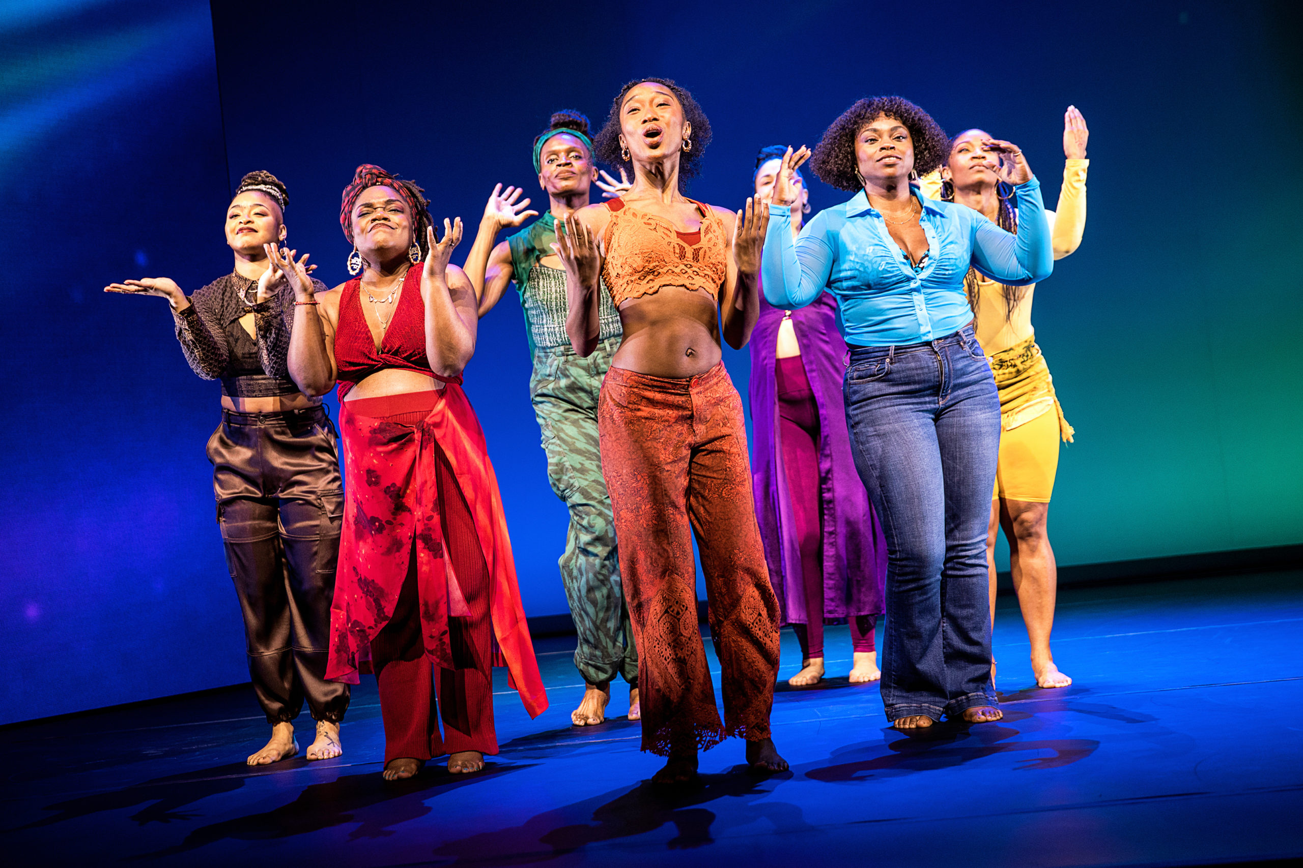 The cast of "for colored girls" are seven Black women, each costumed in a different color of the rainbow, and they stand facing the camera, dancing and singing in unison.