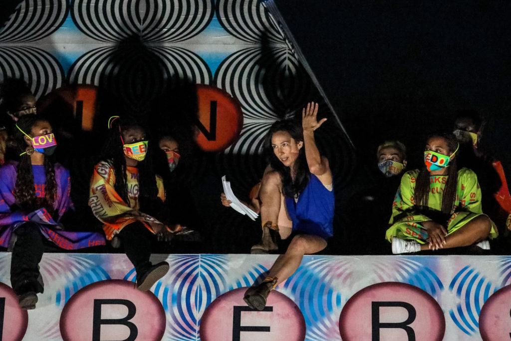 multiple dancers sitting on a colorful wall listening to Johnson 