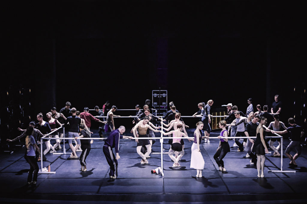 The artists of Kyiv City Ballet do pliés at barres set up on a stage.