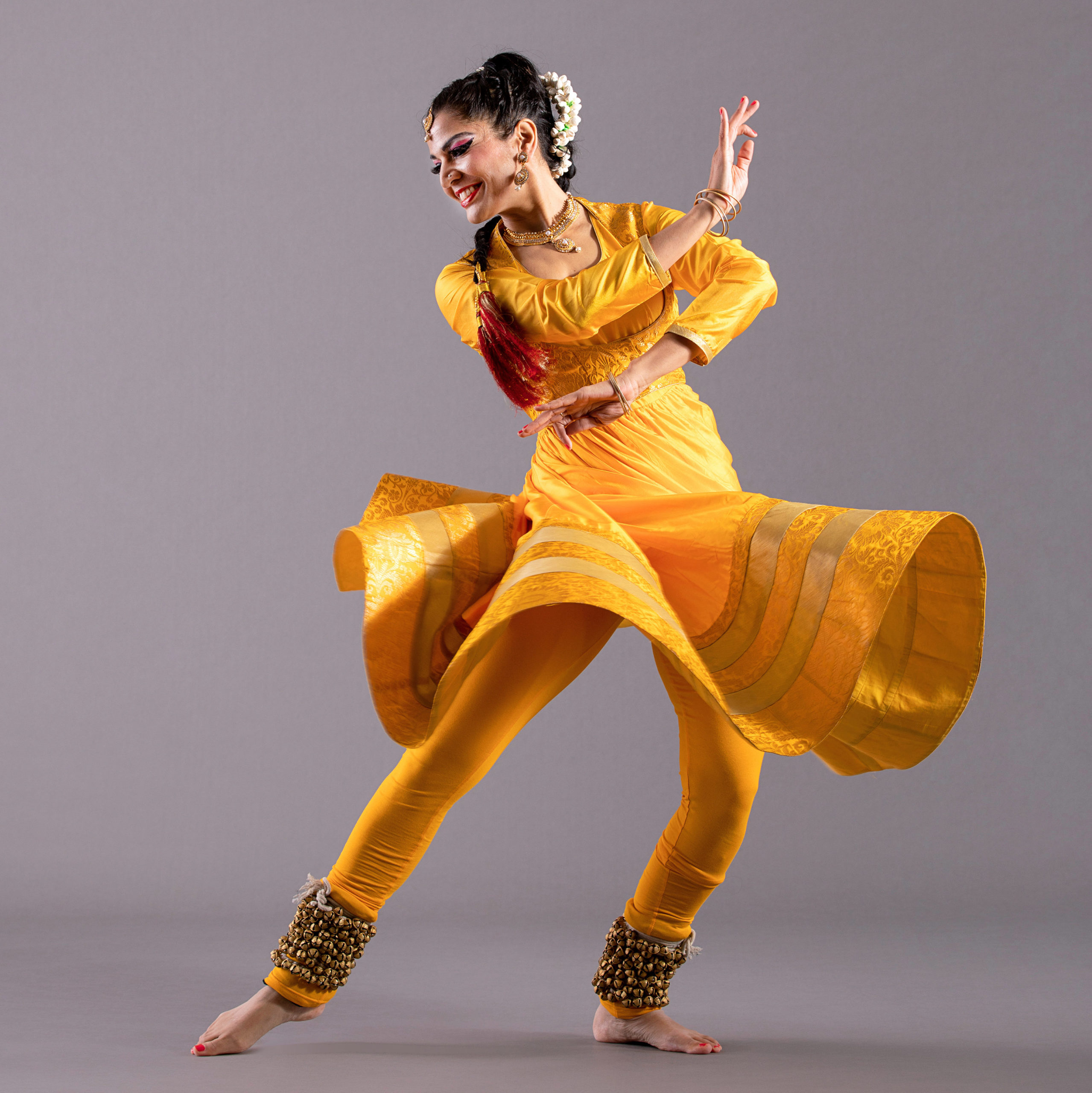 dancer lunging to right arms crossed wearing yellow dress and pants