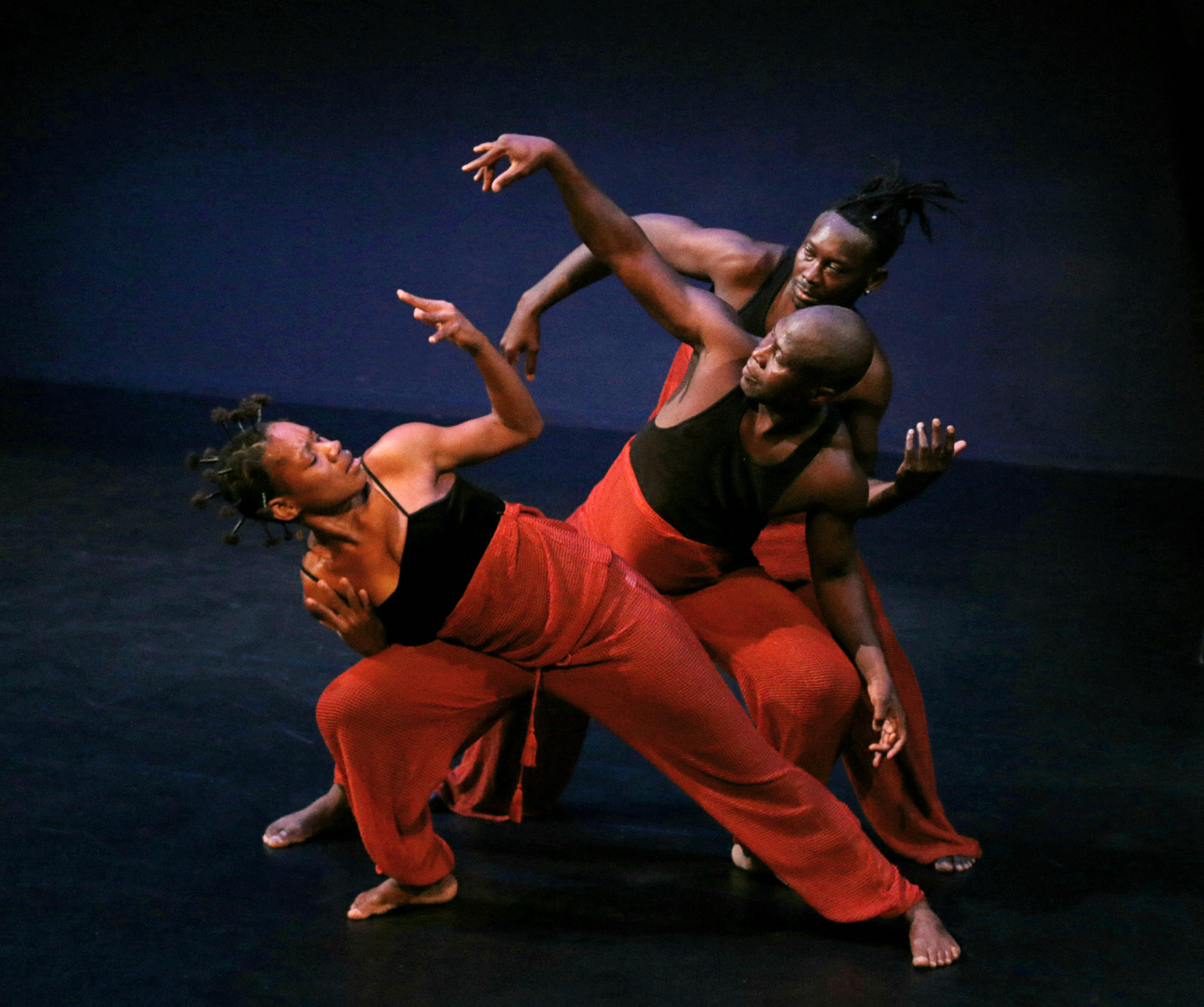 3 dancers wearing red pants and black top