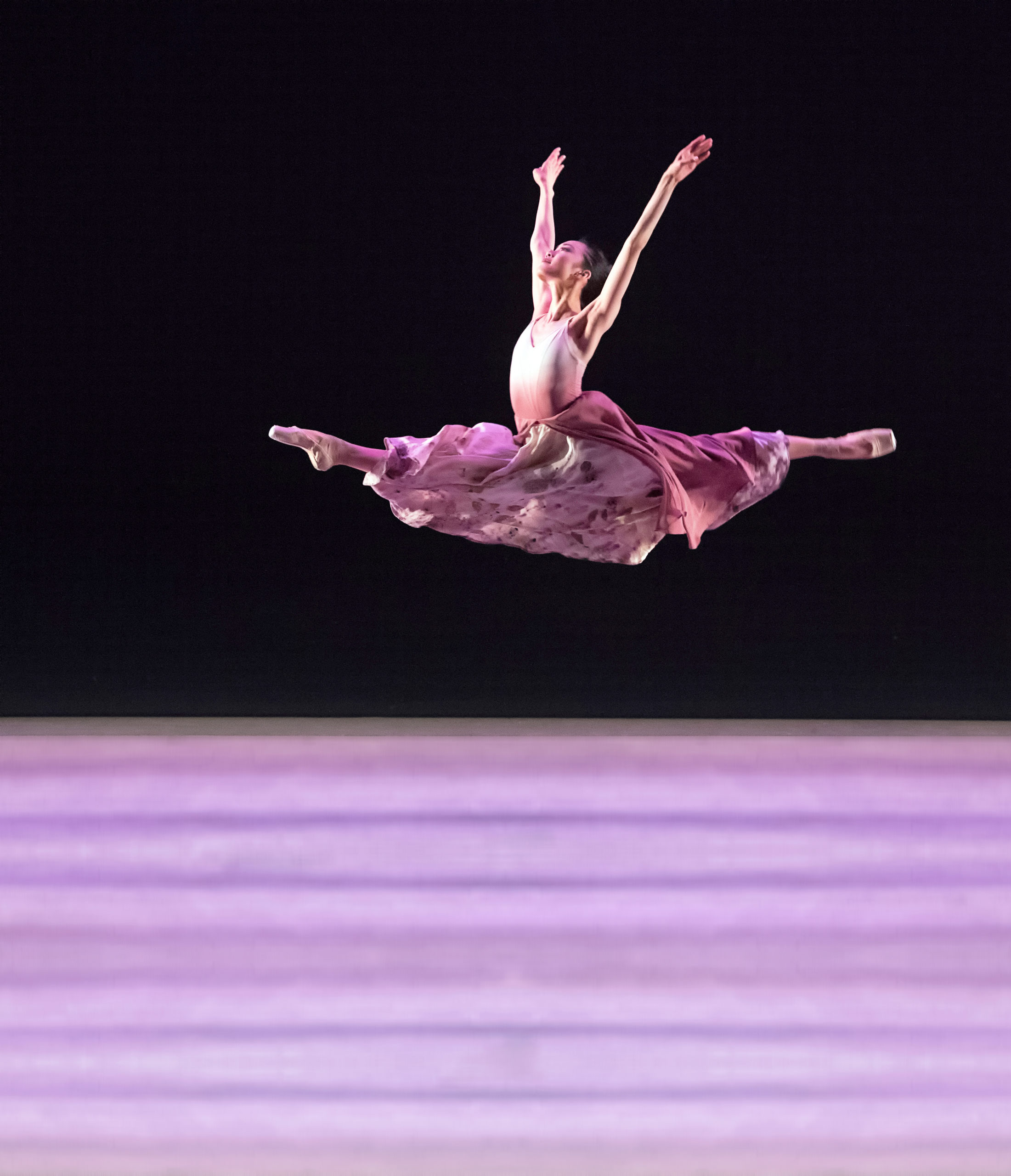 female dancer performing grand jete in long pink skirt