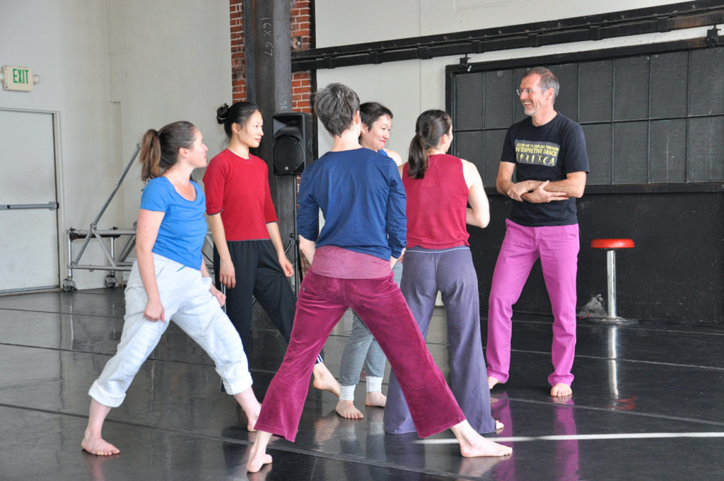 male instructor working with five female dancers 