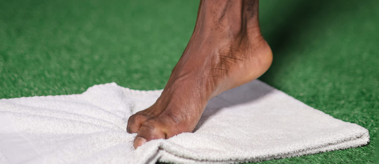 a foot curling a white towel with the toes
