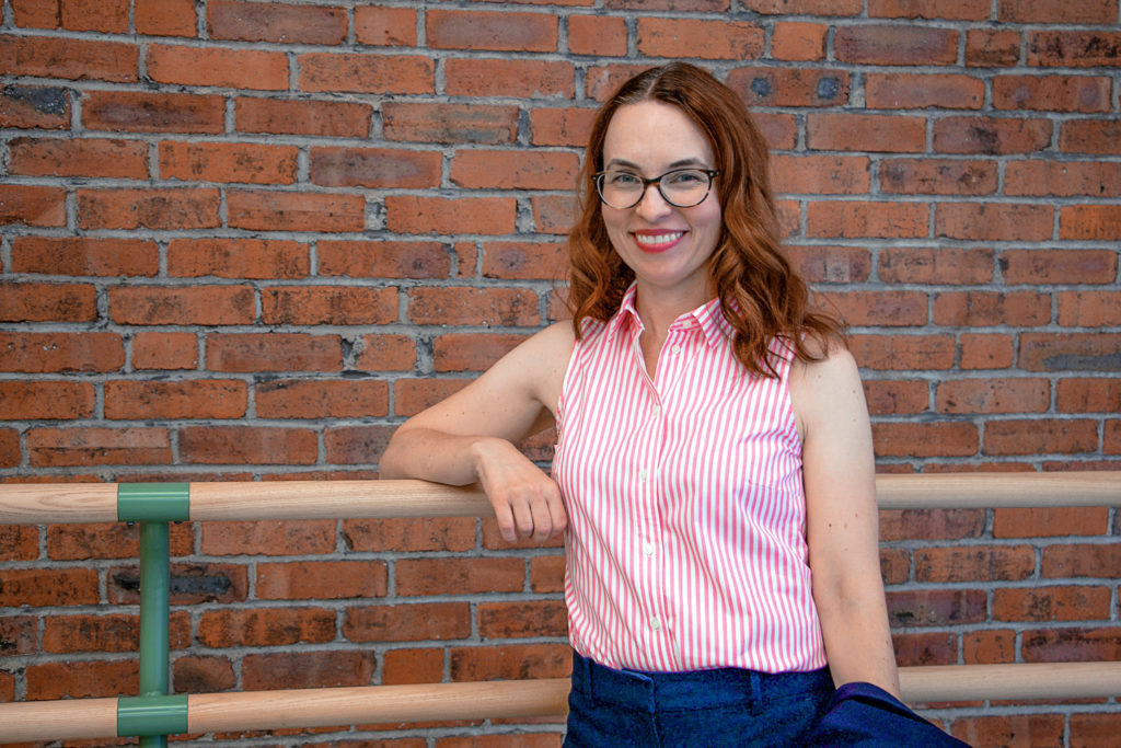 female instructor wearing red striped shirt smiling at camera 