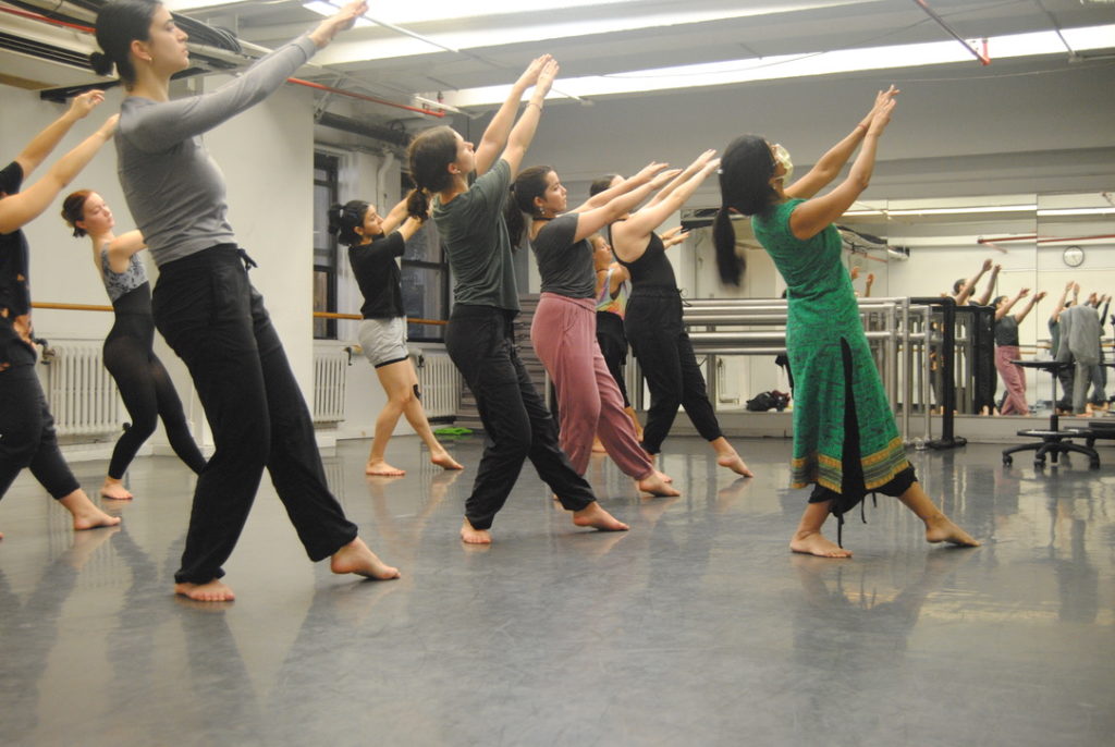 Parul Shah, in green traditional Indian clothing, leads students in a Kathak class.
