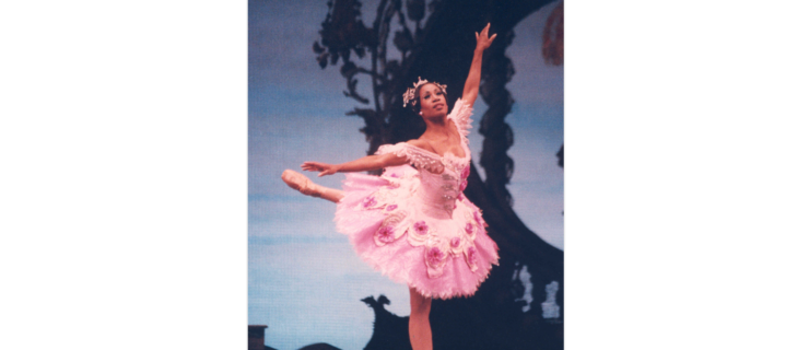 A vintage performance photo of Lauren Anderson as the Sugarplum Fairy. She is wearing a pink tutu and pointe shoes and balancing in attitude.