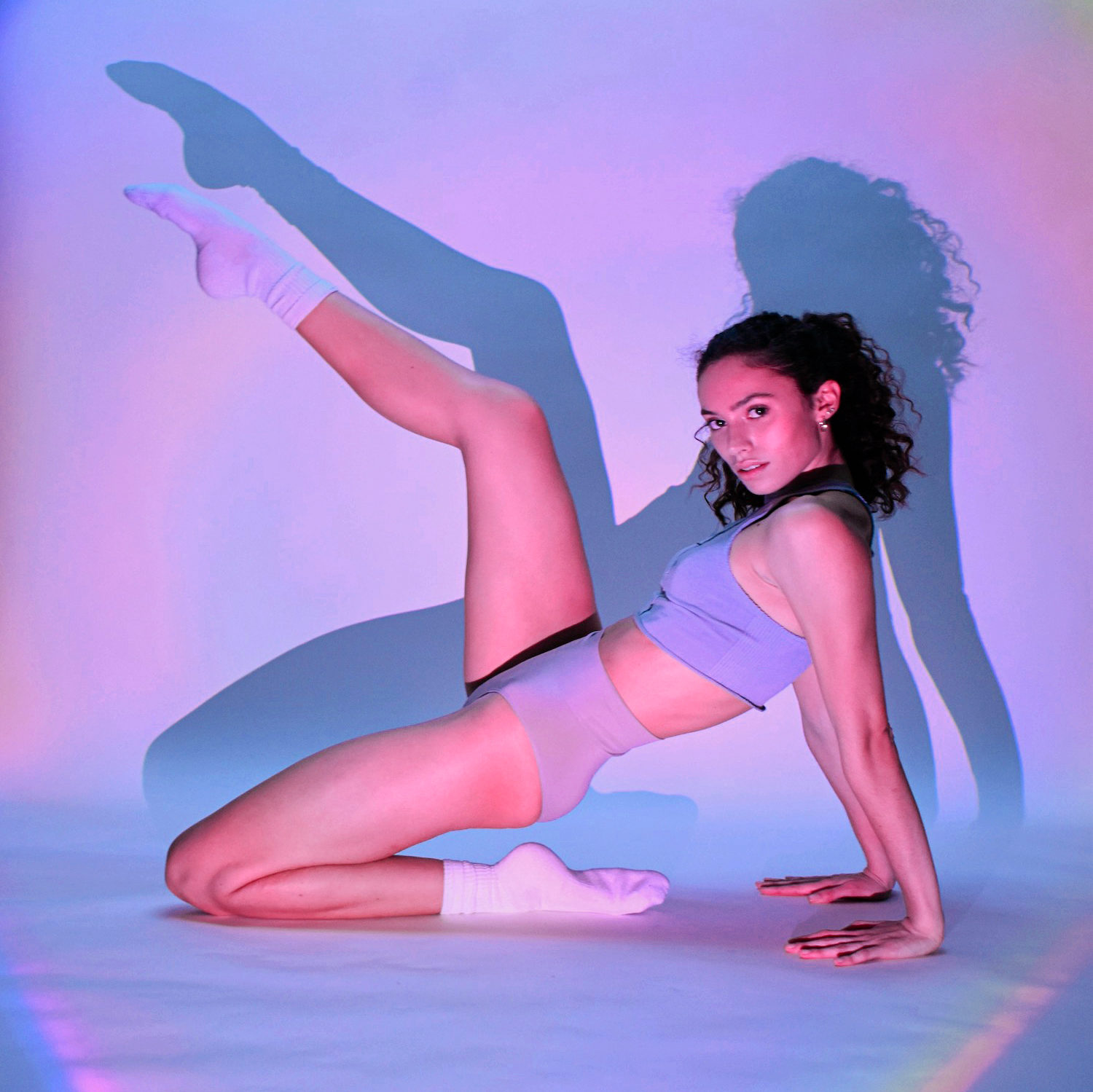 female dancer posing in front of backdrop with purple lights