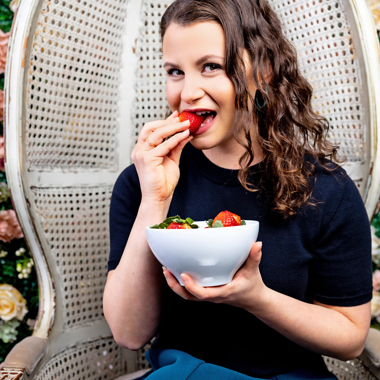 female sitting in large white chair eating strawberries 
