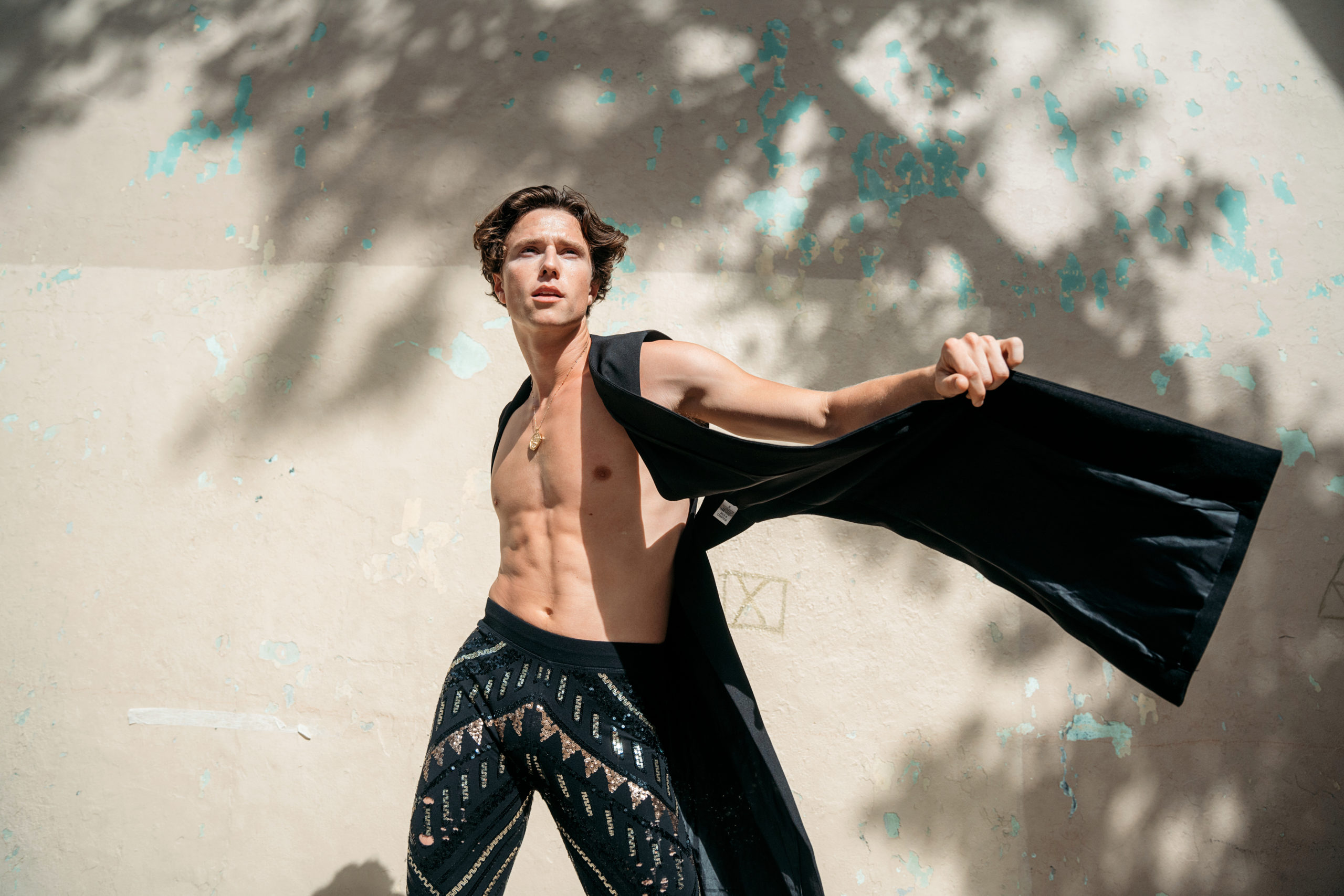 male dancer wearing long cape and patterned pants