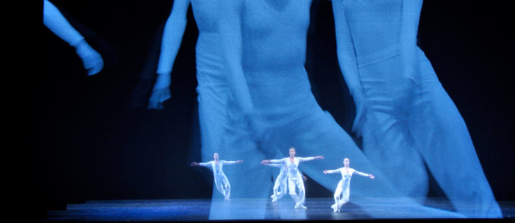 3 dancers wearing white performing on stage