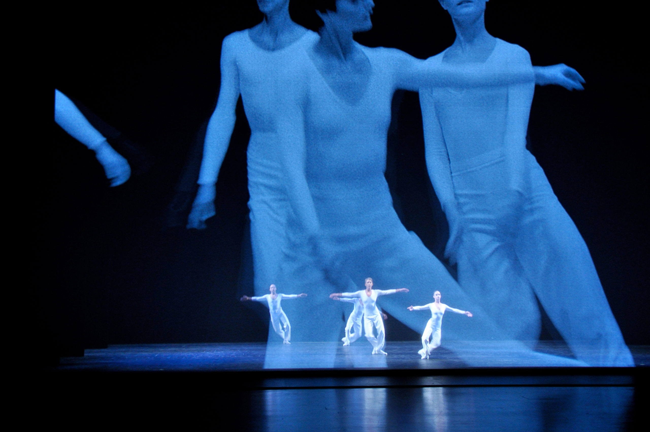 3 dancers wearing white performing on stage