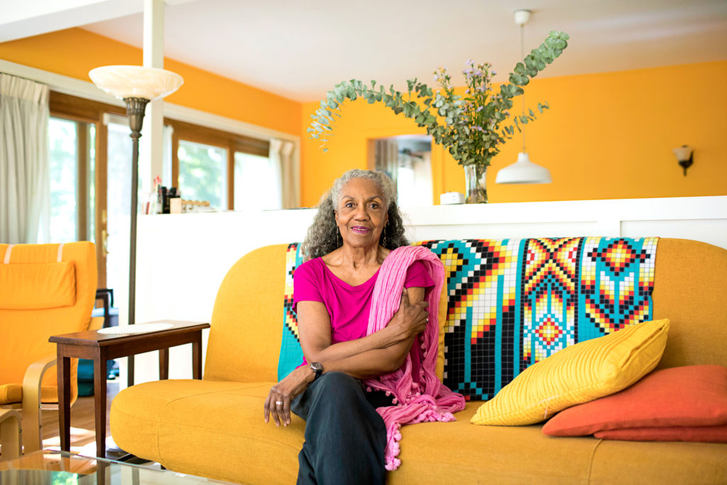 female sitting on a bright yellow couch smiling at the camera