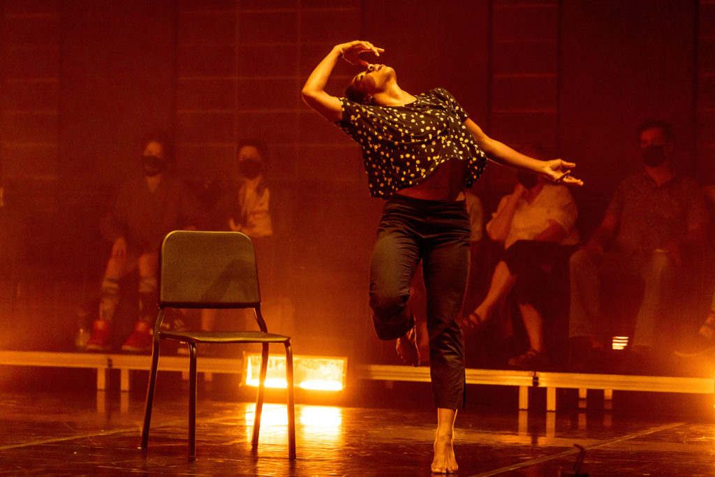 female dancer performing on stage next to a chair