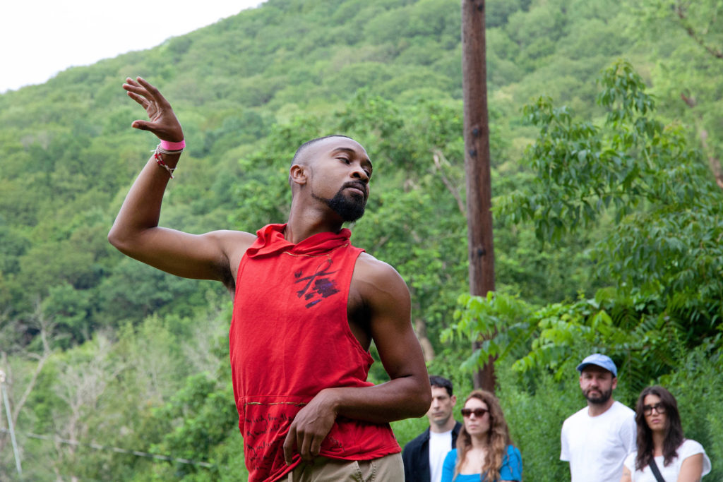 male dancer wearing red tank top dancing outside 