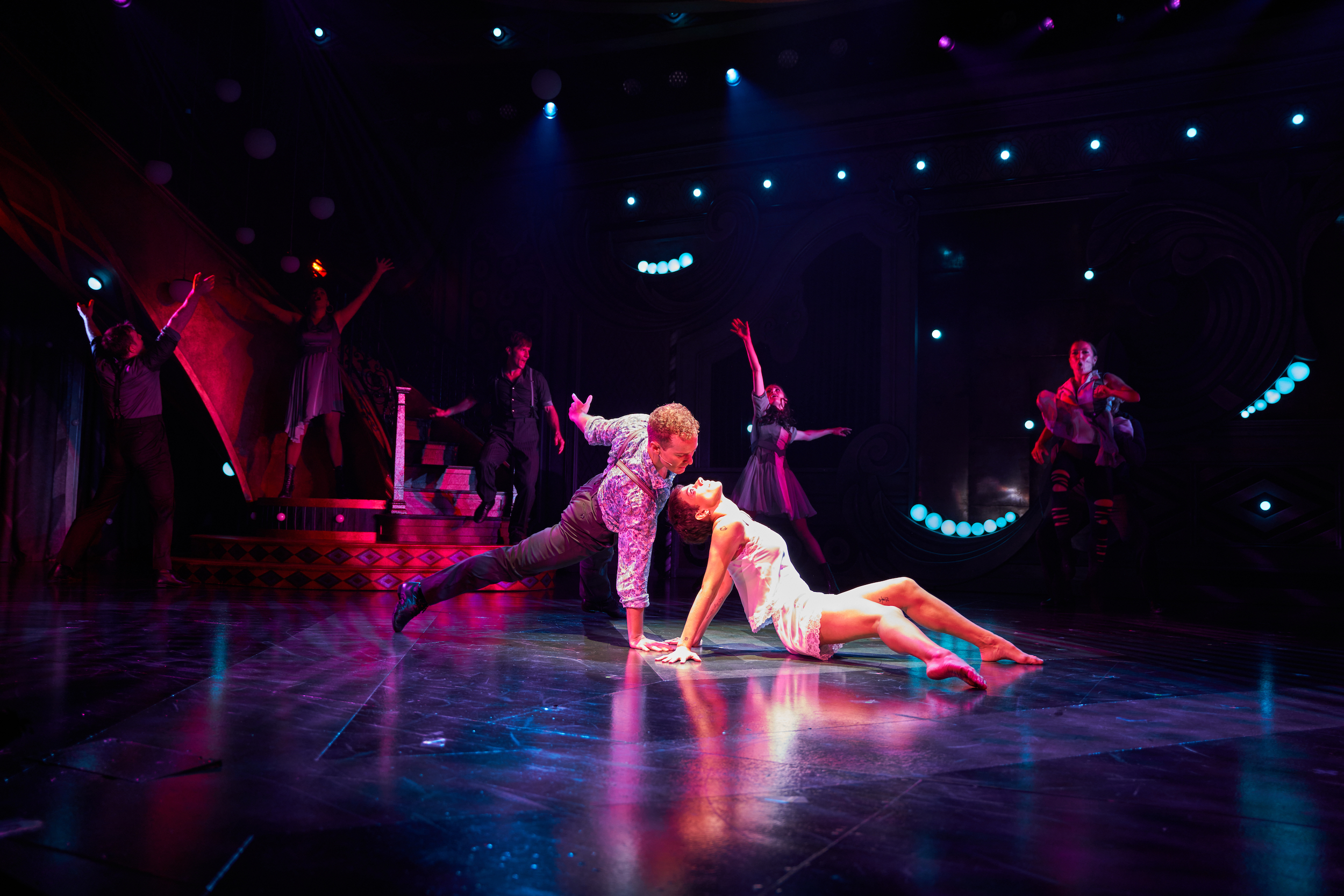 A man lunges downward hovering over his female dance partner as she arches back toward his face.