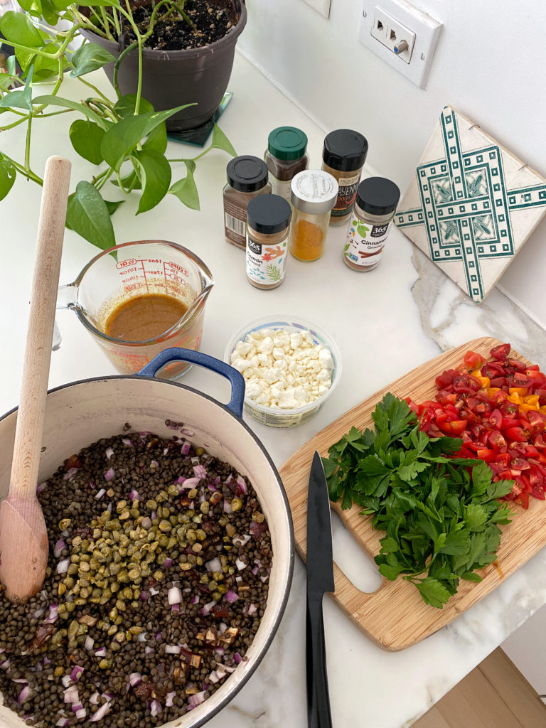 bowl with lentils, cutting board with herbs  and peppers, spices