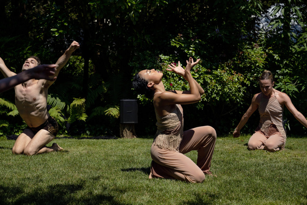 dancer wearing nude colored costumes kneeling in the grass