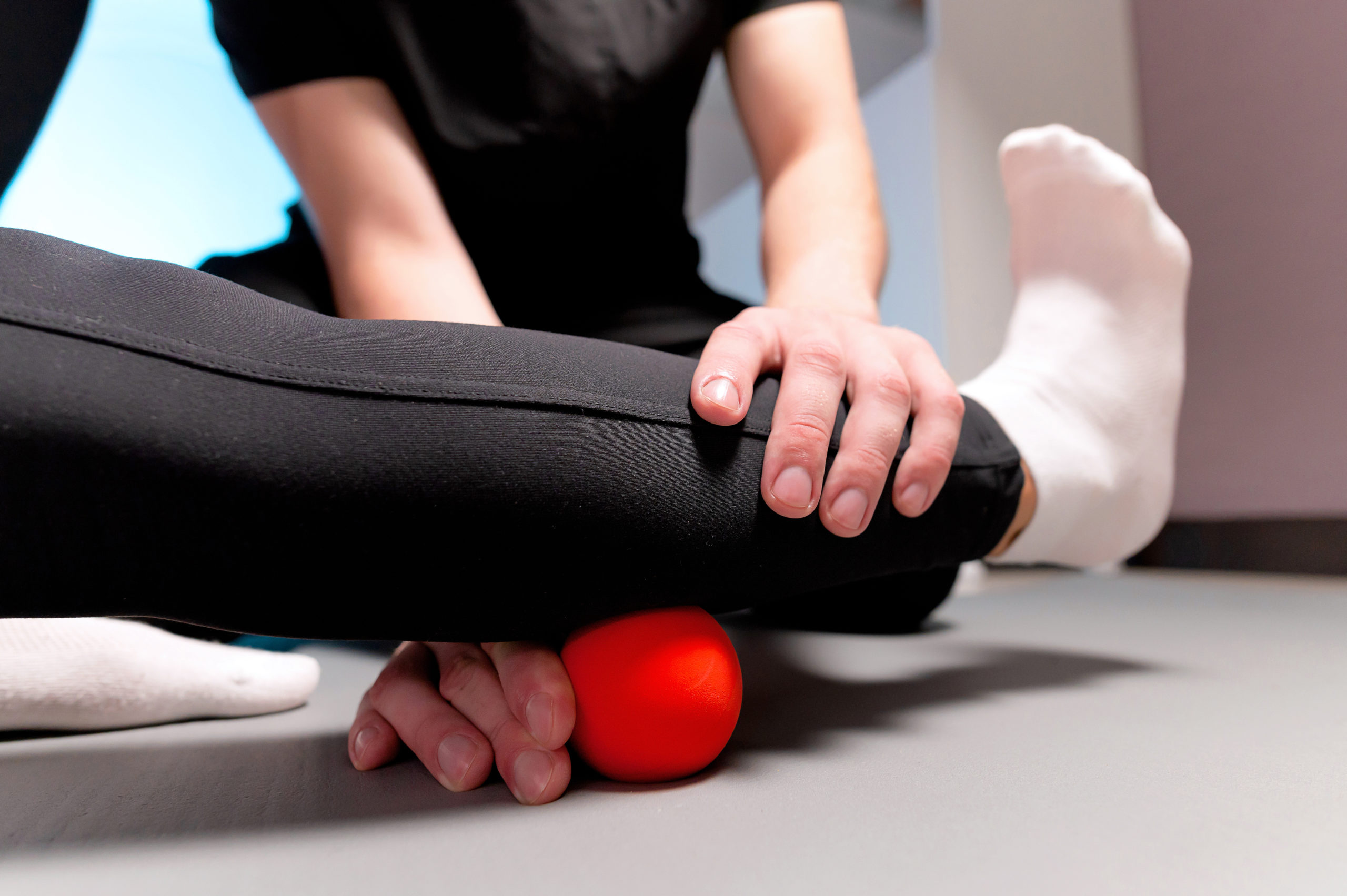 Close-up young male massage therapist teaches a client Caucasian woman myofascial self-massage using a massage ball indoors. Myofasceal release.