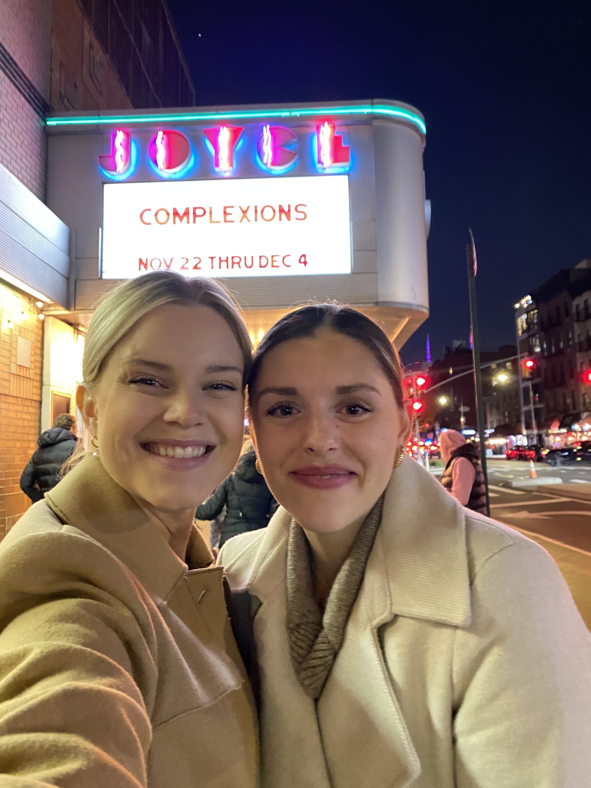 two women stand in front of a Joyce theater marquis that says Complexions