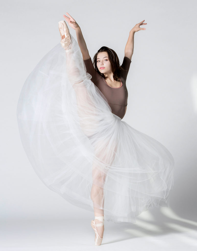 female dancer wearing long skirt performing develope side
