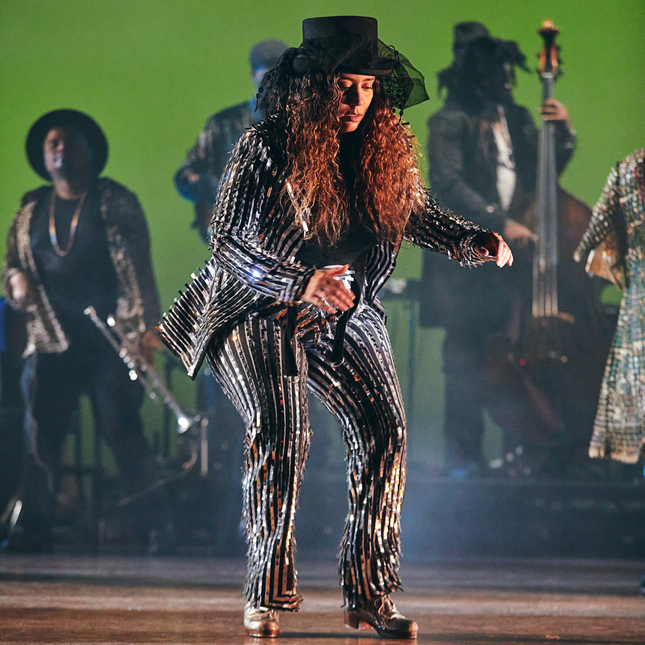 female dancer wearing black hat and striped suit dancing on stage